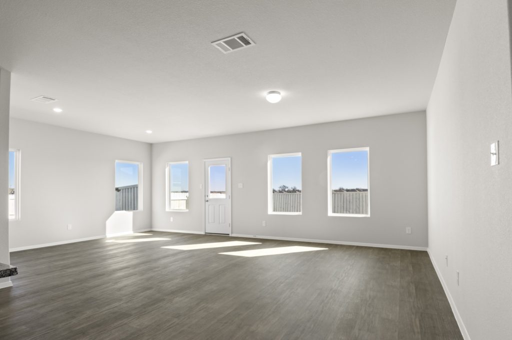 Image of a living room with light grey walls, dark brown floorings, white trim and windows