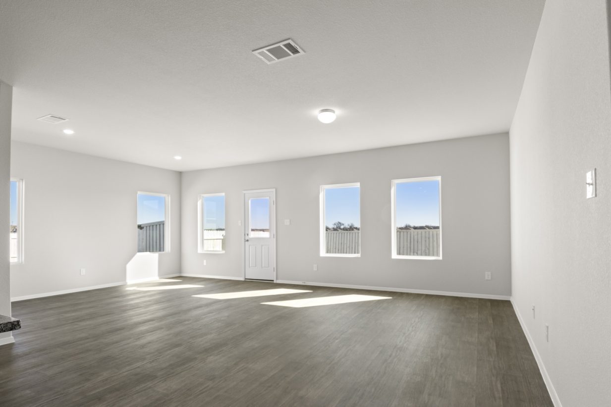 Image of a living room with light grey walls, dark brown floorings, white trim and windows