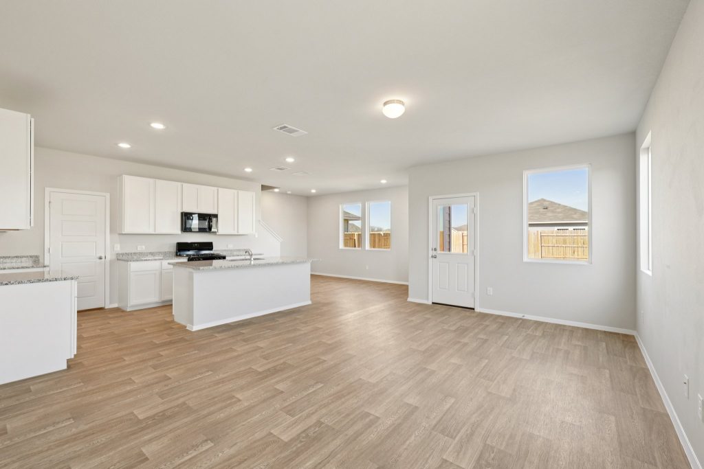 Image of a living room open to a kitchen with white cabinets