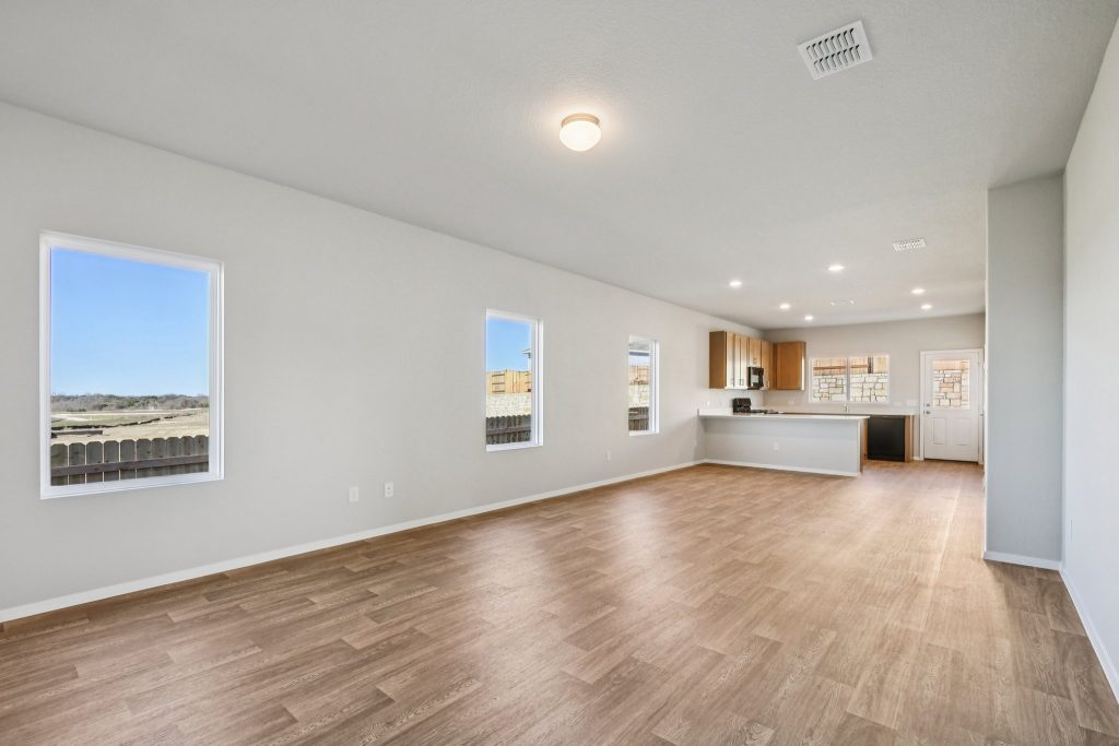 Image of a living room with light grey walls, vinyl flooring, windows and white trim
