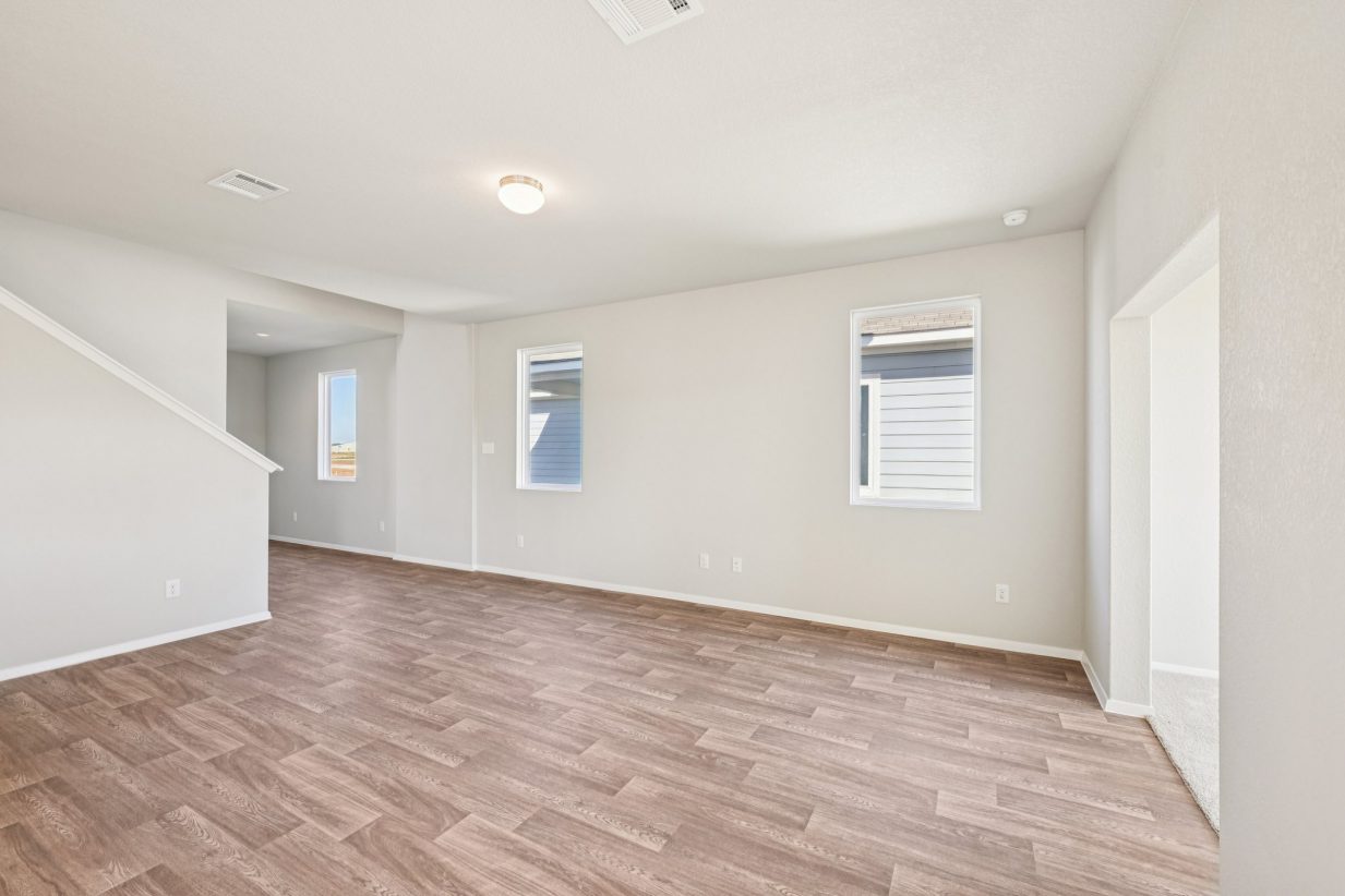 Image of a living room area with vinyl flooring, beige walls and windows
