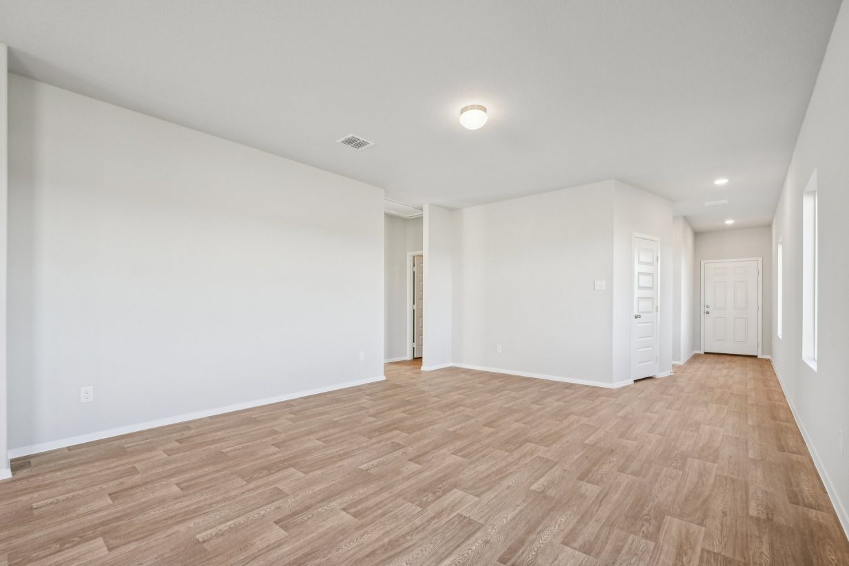 Image of a living room area with light grey walls, vinyl flooring, and white trim