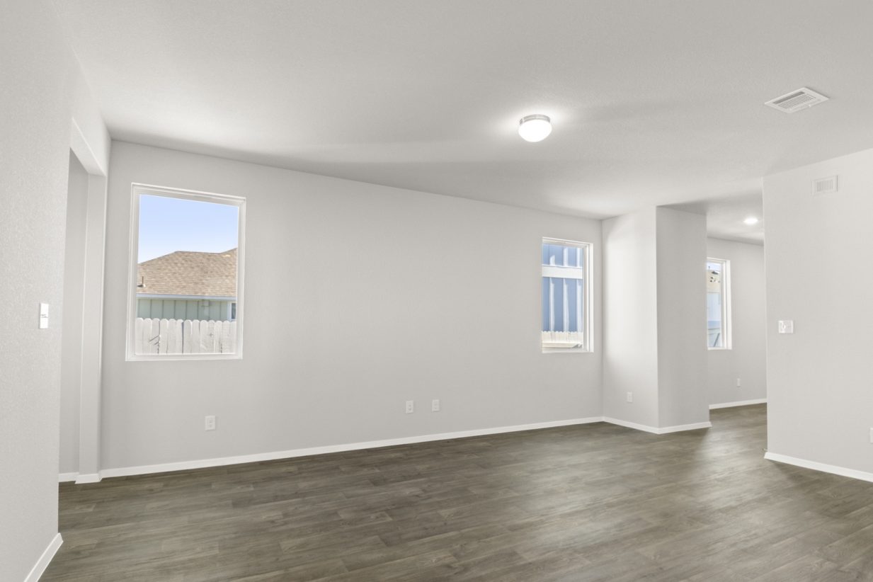 Image of a living room with dark vinyl flooring, light grey walls, and two windows
