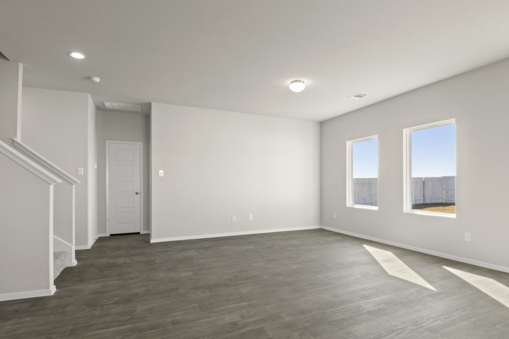 Image of a living room with cream walls, two windows, dark brown flooring and white trim