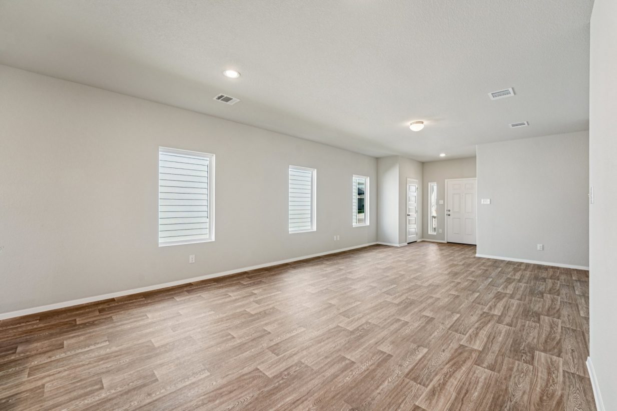 Image of a living and dining area with vinyl flooring, grey walls and windows