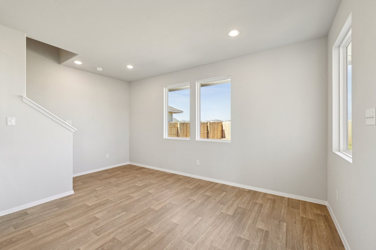 Image of a dining room with grey walls, vinyl flooring, white trim and a staircase