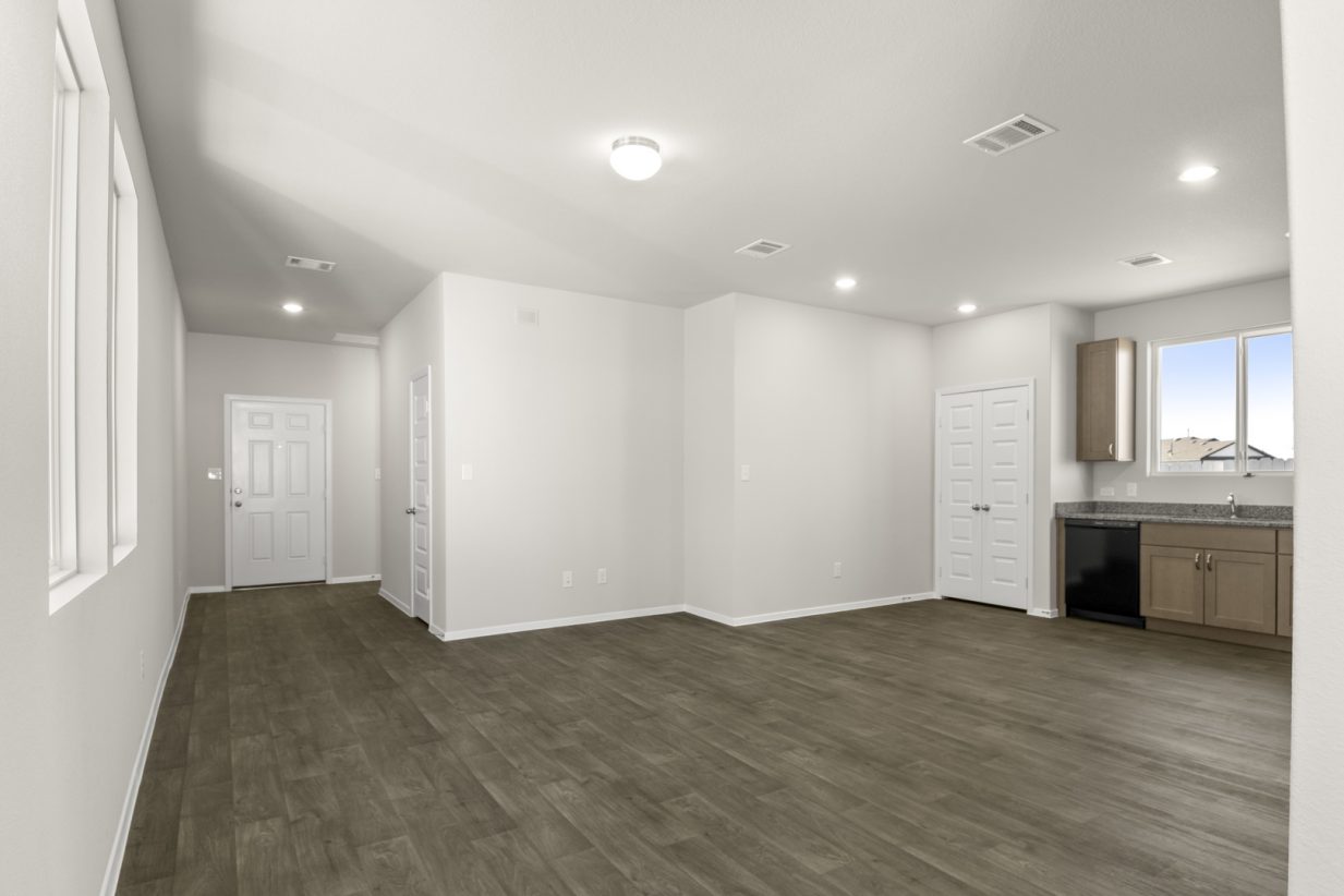 Image of a living room with dark vinyl flooring and light grey walls with white trim and a front door entryway