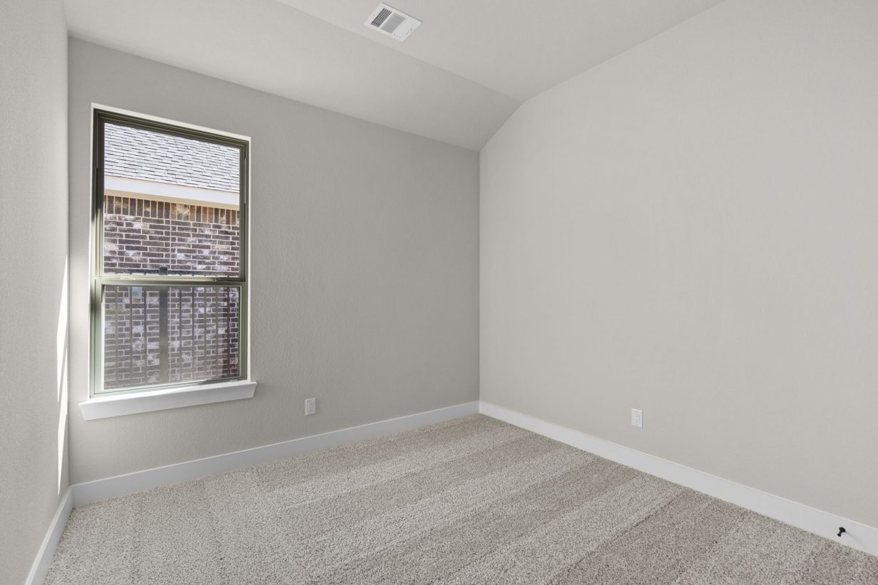 Image of a bedroom with beige walls, tan carpeting and a brown window with tan trim