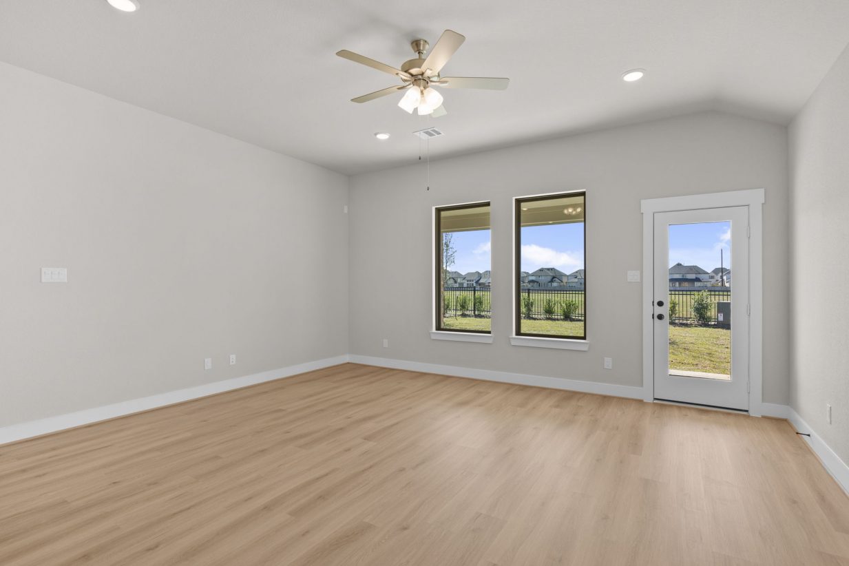 Image of a living room with beige walls, light brown floors, windows and a ceiling fan