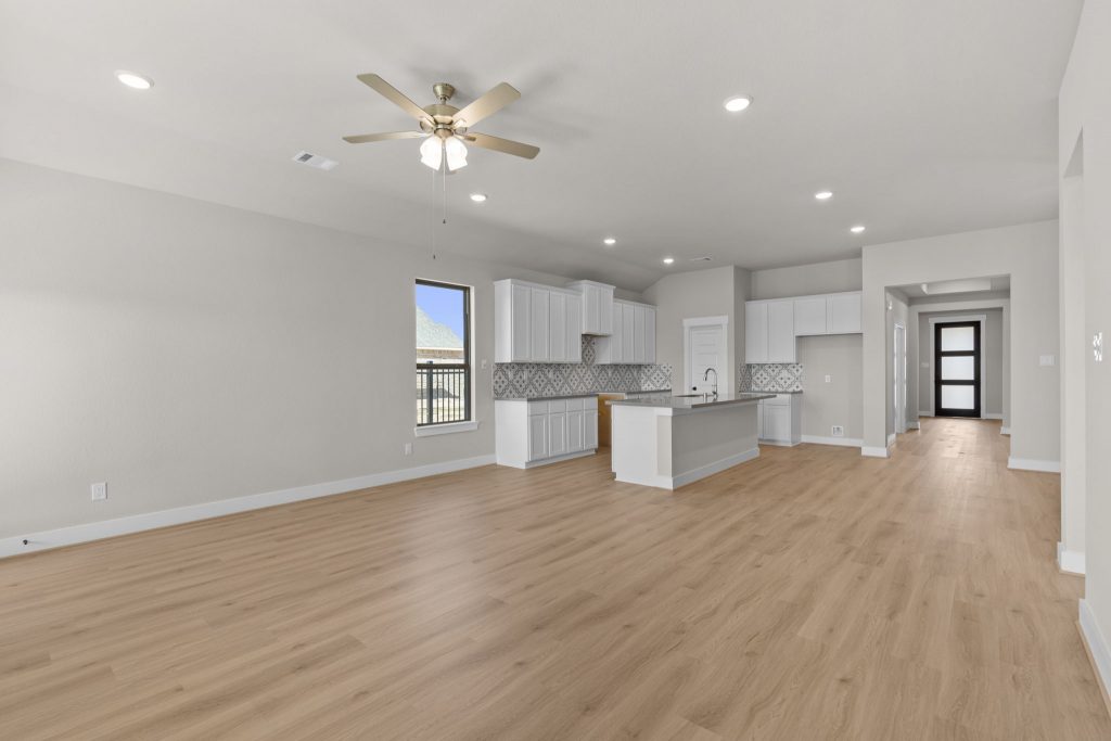 Image of a living room with beige walls, light brown flooring and a ceiling fan