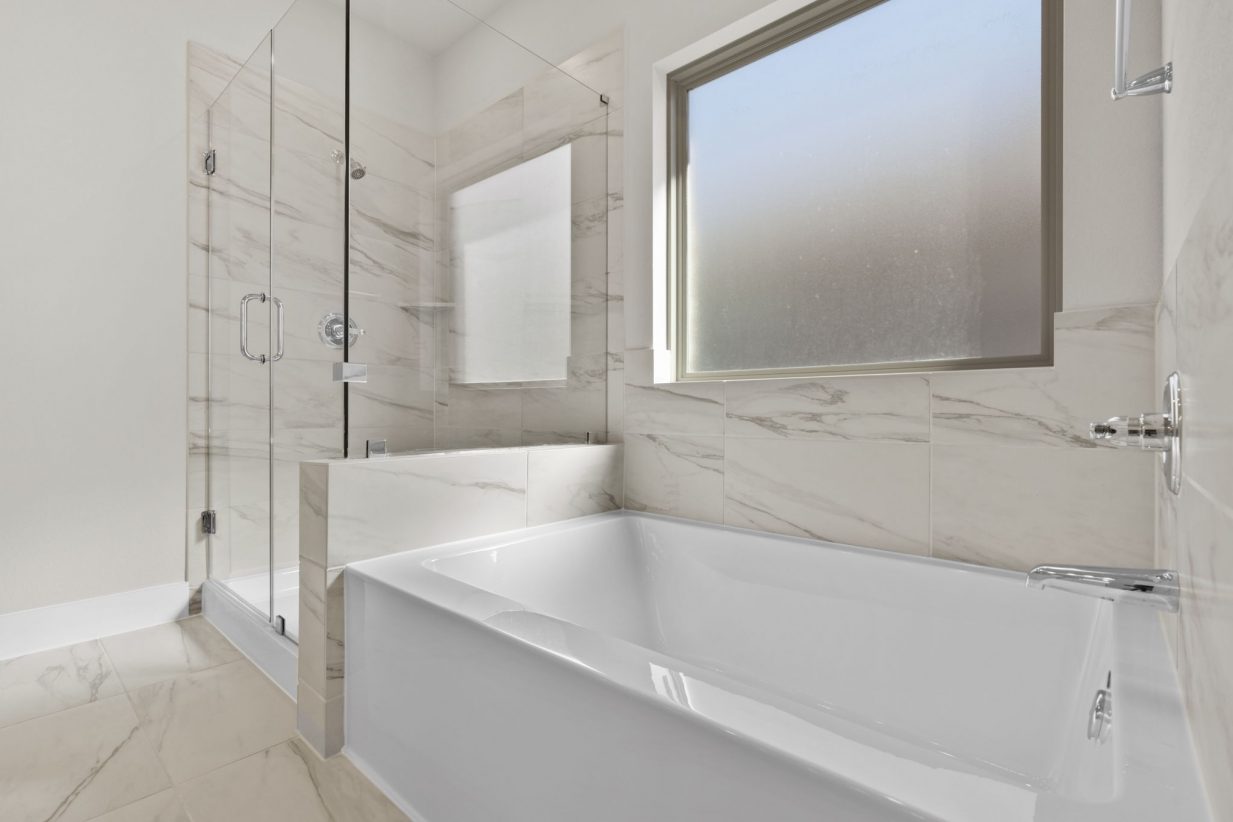 Image of a primary bathroom with a standing shower, a garden rub and a window