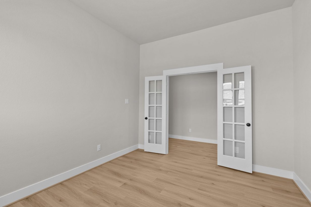 Image of a study room with beige walls, with french doors, with white trim