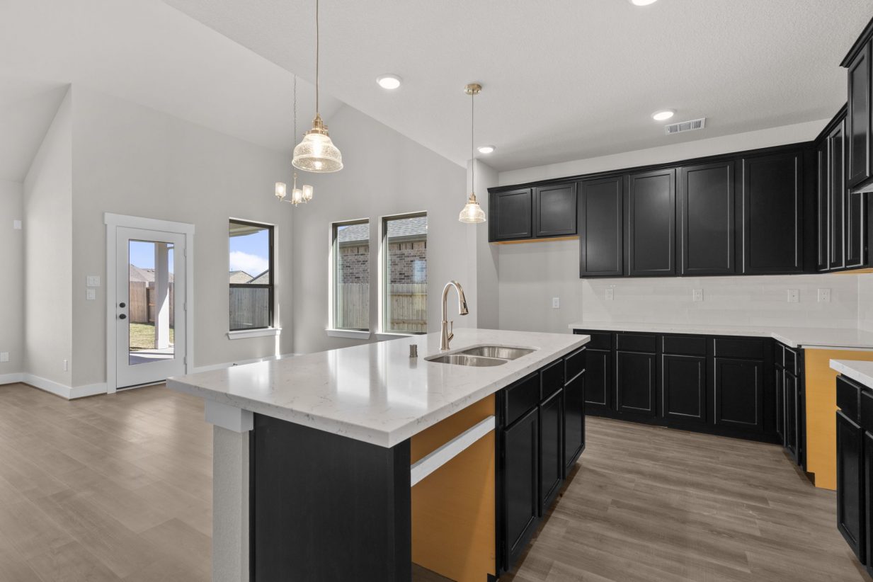 Image of a kitchen with black cabinets, a center island, white counter tops, and light fixtures