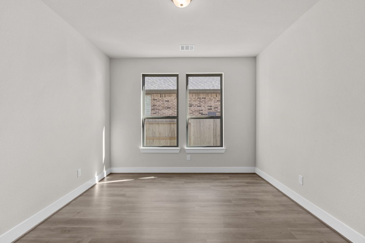 Image of a study room with beige walls, light brown flooring, two windows with black trim