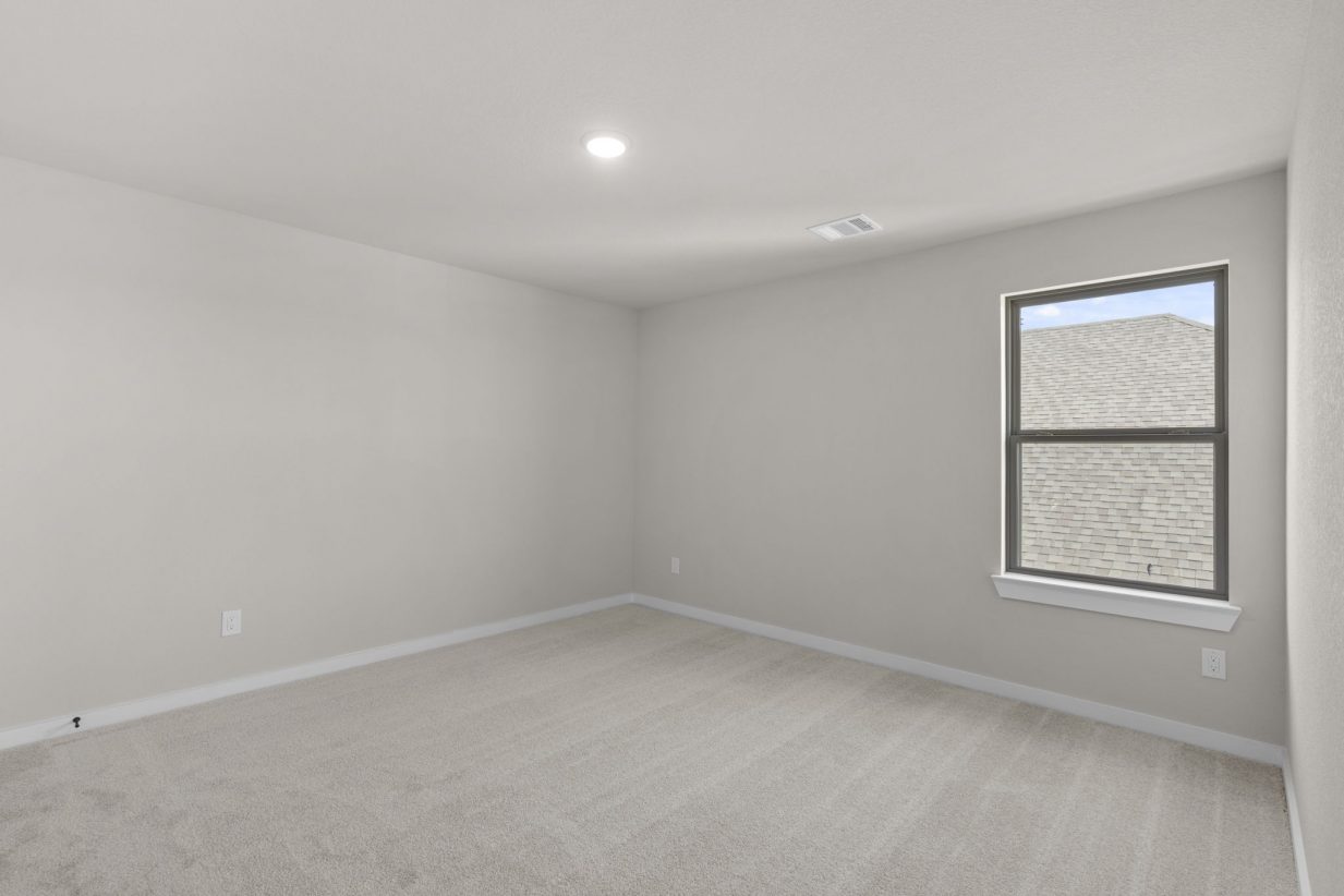 Image of a bedroom with tan carpeting and white walls, and a window with black trim