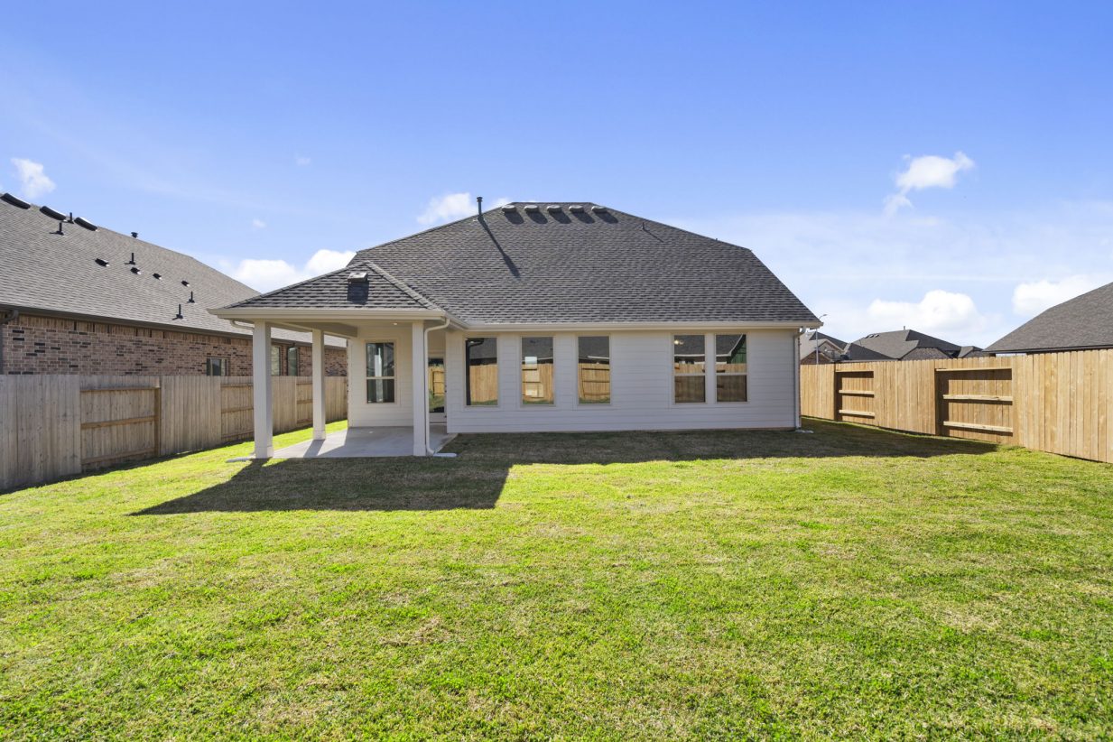Image of the back exterior of a home with green grass and a blue sky