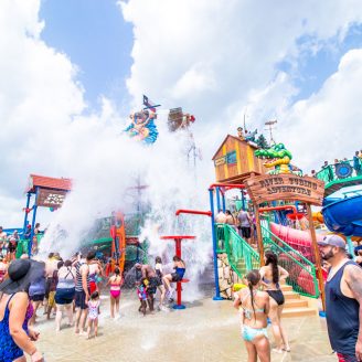 New-Caney-attractions Kids splashing at Big Rivers Waterpark while others zipline overhead near New Caney, Texas.