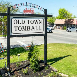 Tomball Brohn Homes new construction neighborhood in Tomball with modern homes and tree-lined streets, showing historic downtown charm in background.