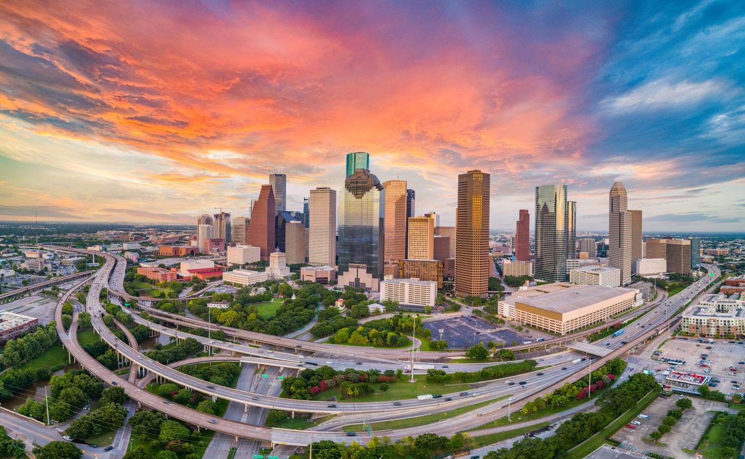 Aerial view of downtown Houston skyline at golden hour with highways and urban landscape, showcasing the location advantages of Brohn Homes communities