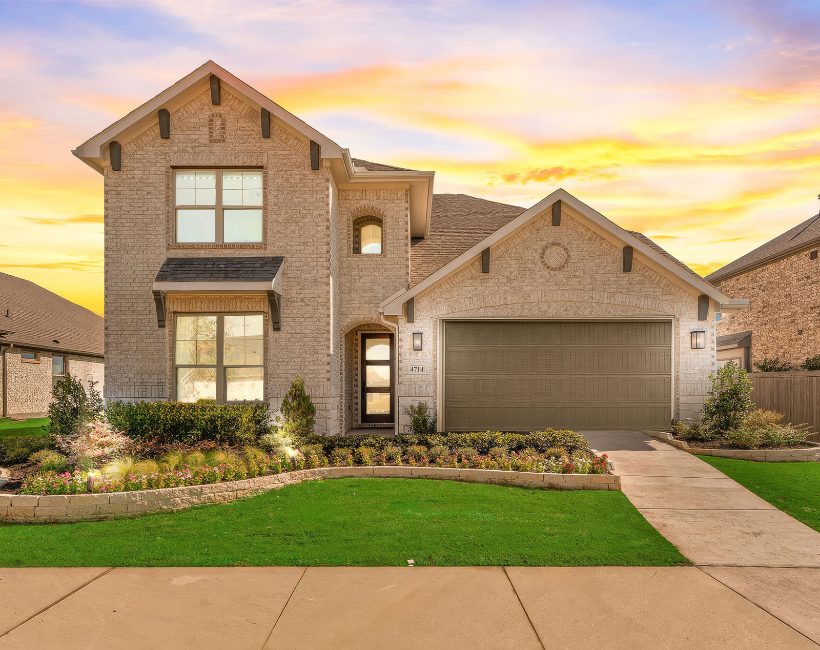 Beautiful new construction brick home at sunset with two-car garage and professionally landscaped front yard at Brohn Homes Houston.