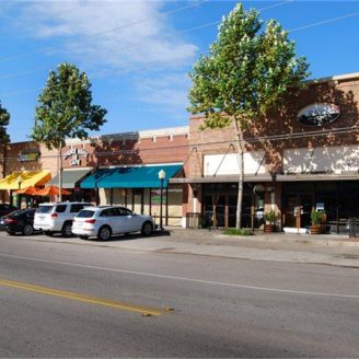 dowtown fulshear Shoppers carrying bags outside a mix of local boutiques and modern retail centers in Fulshear, Texas.