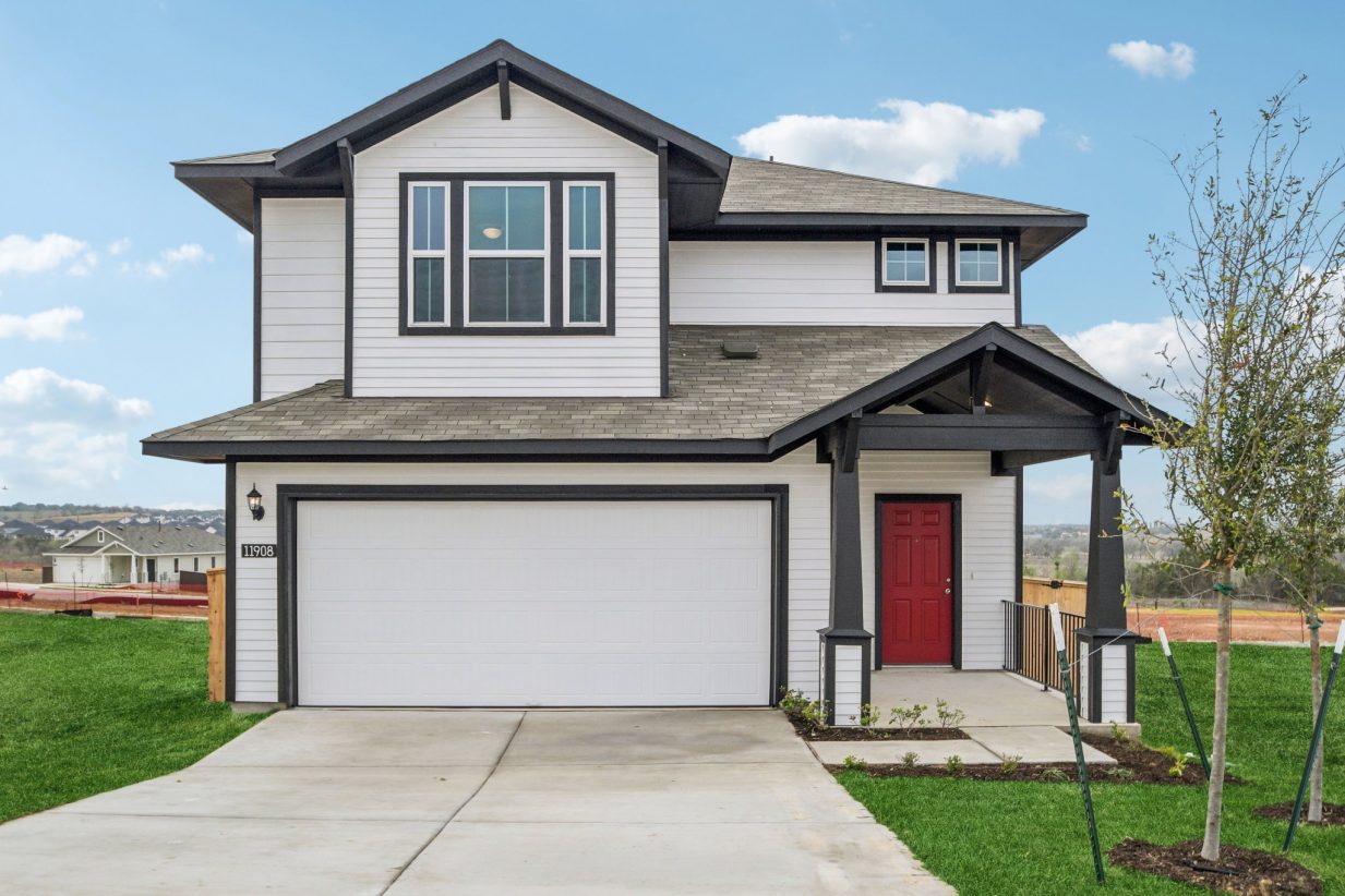Image of a white two story house with black trim, red front door, a green grass front yard and a blue sky in the background