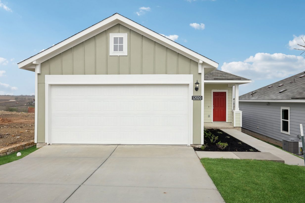 Image of a one story green house with a red front door