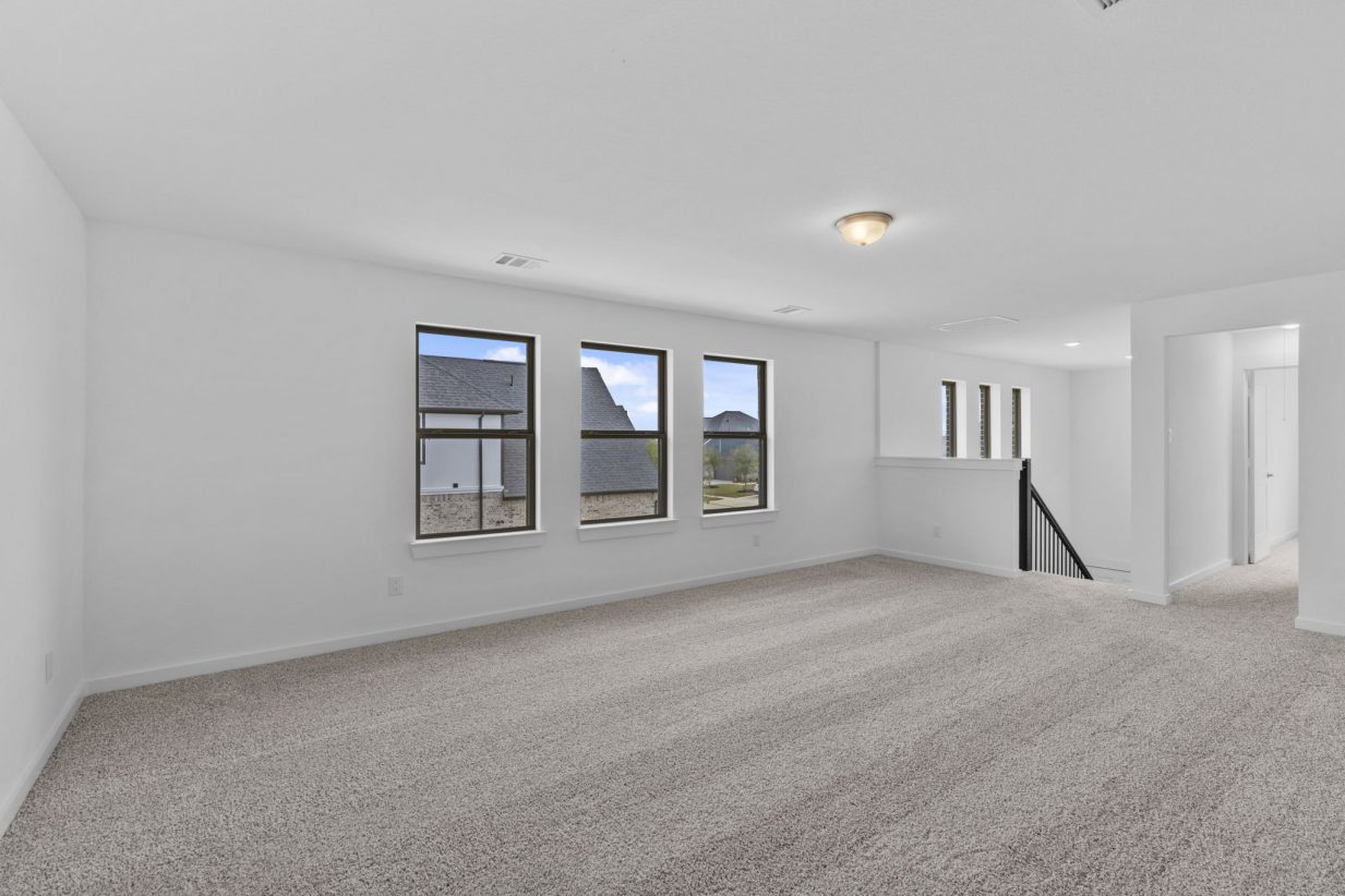 Image of a gameroom with tan carpeting, white walls and windows with brown trim