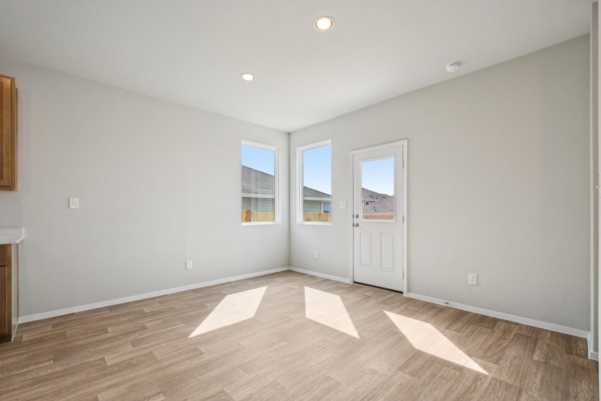 Image of a dining room area with light brown vinyl flooring, light grey walls, windows and a white back door
