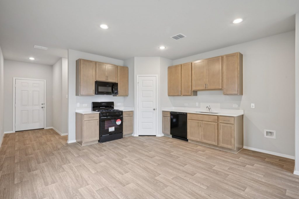 Image of a kitchen with brown cabinets, black appliances and a corner pantry