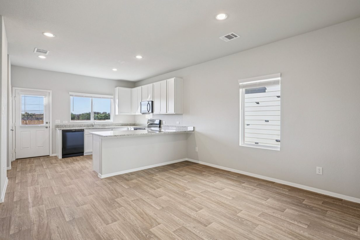 Image of a kitchen and dining area with a U-shaped kitchen, windows and a back door
