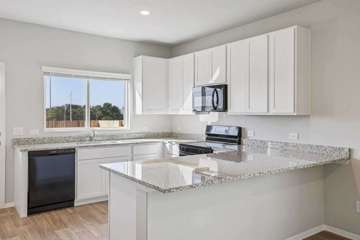 Image of a kitchen with white cabinets, granite countertops, black appliances, and a window above the sink