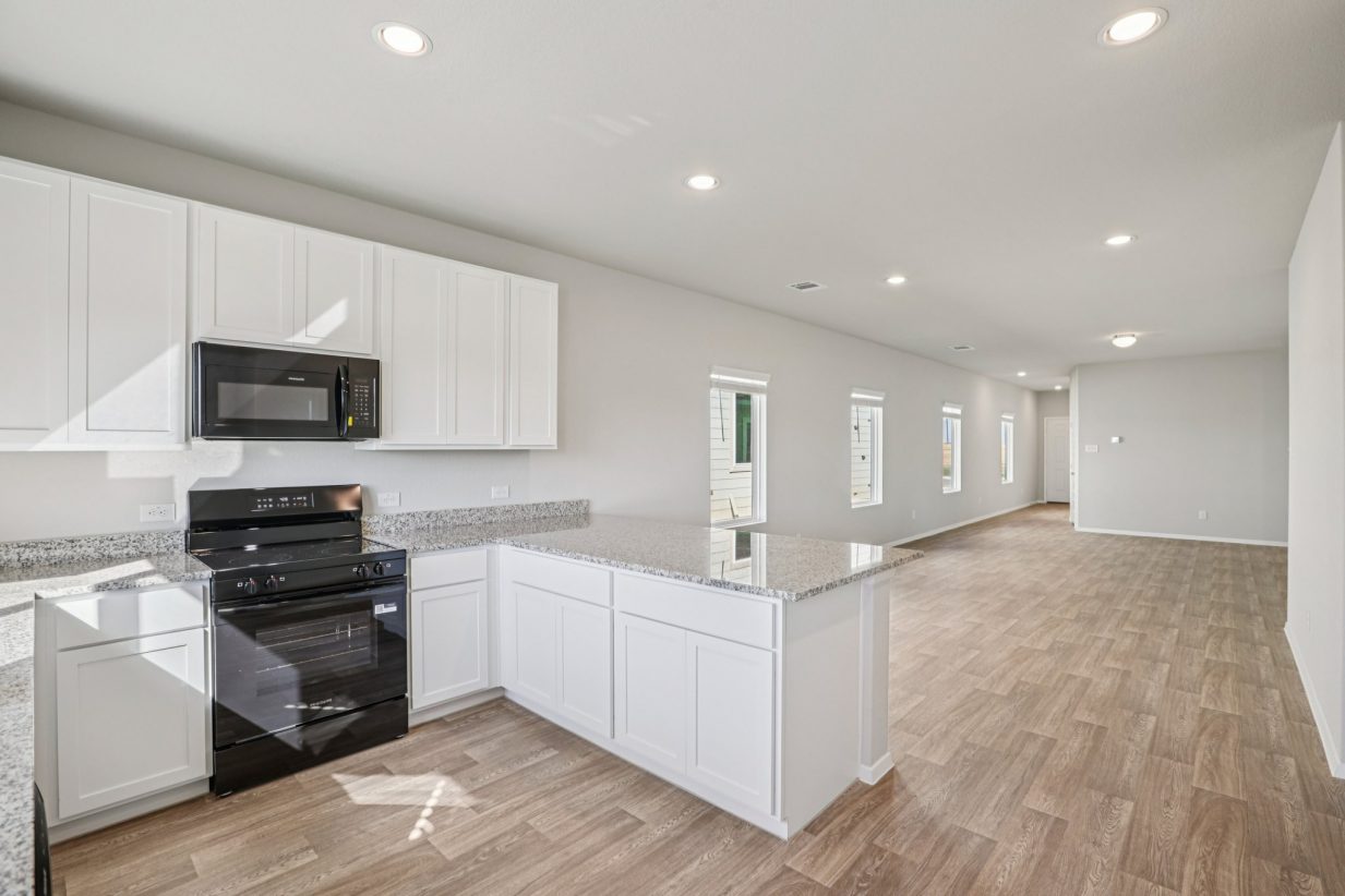 Image of a kitchen with white cabinets, granite countertops, and black appliances
