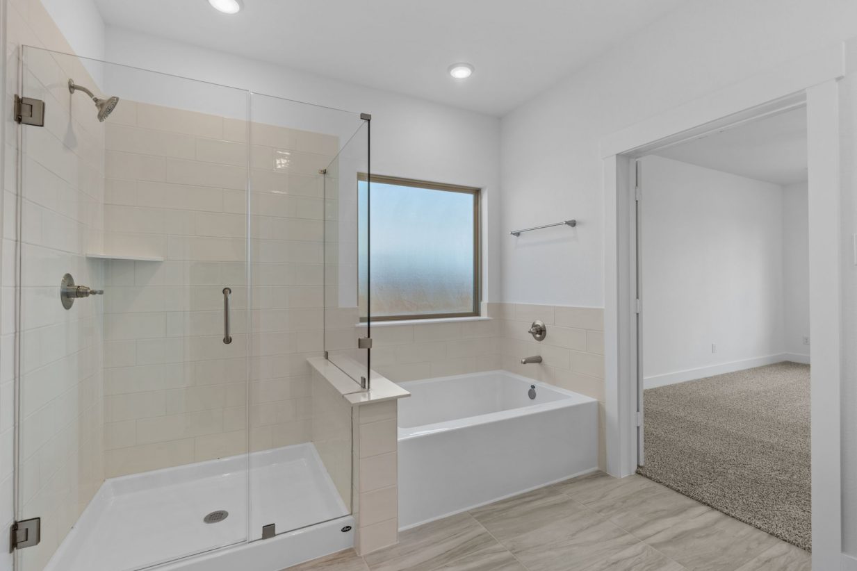 Image of a bathroom with a glass walk-in shower, a white garden rub, a large mirror and beige tiles