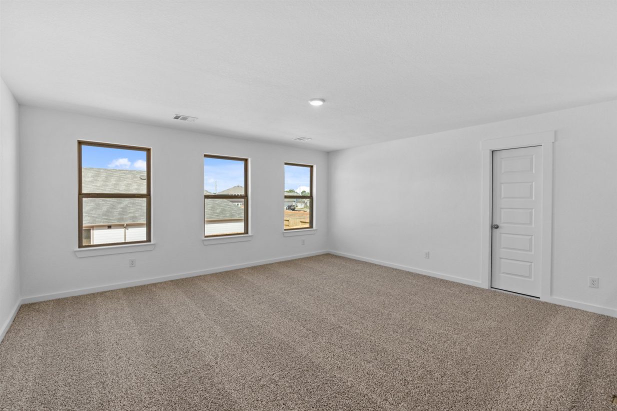 Image of an upstairs game room with white walls, brown carpeting, three windows with brown trim