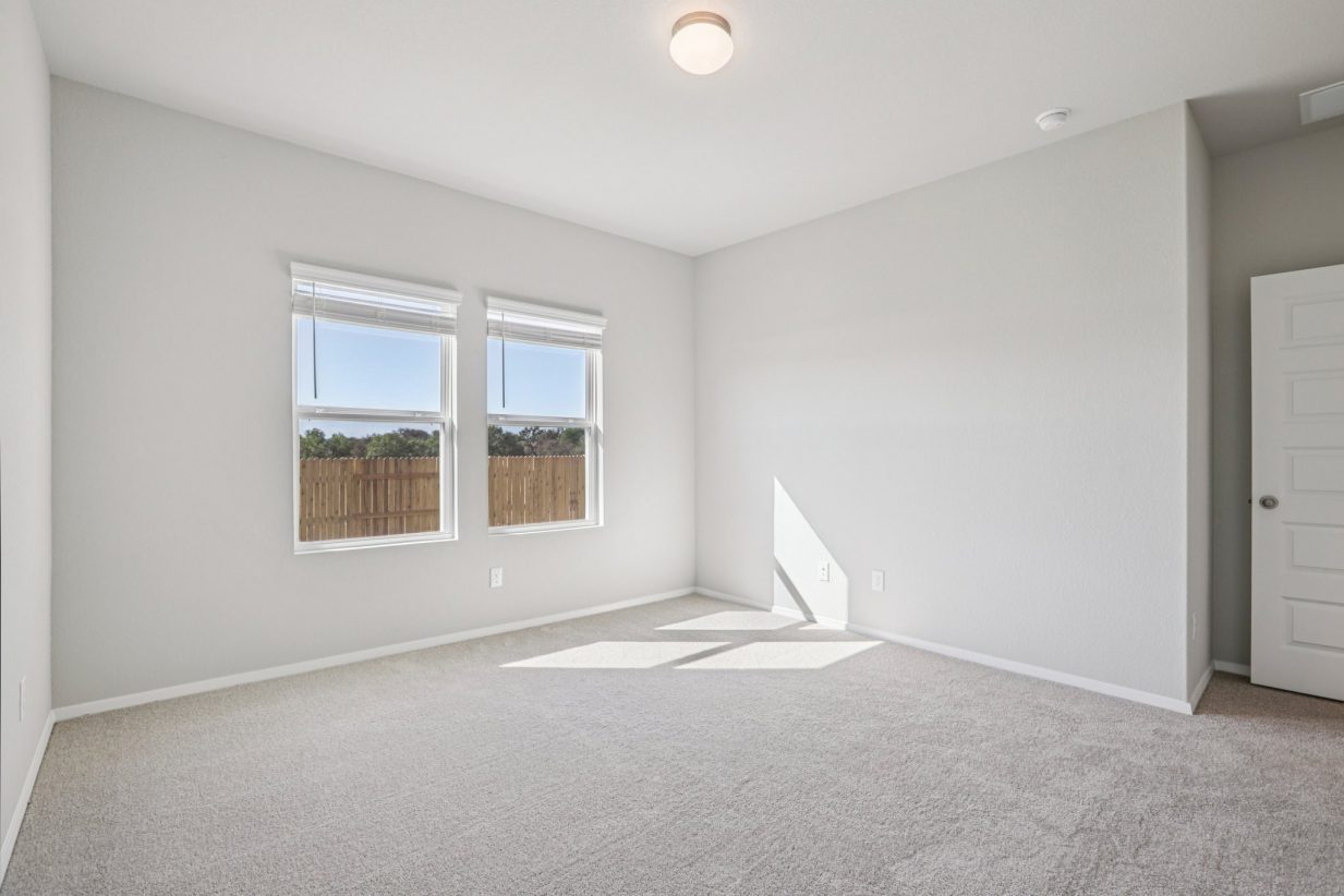 Image of a primary bedroom with grey walls, carpeting and windows