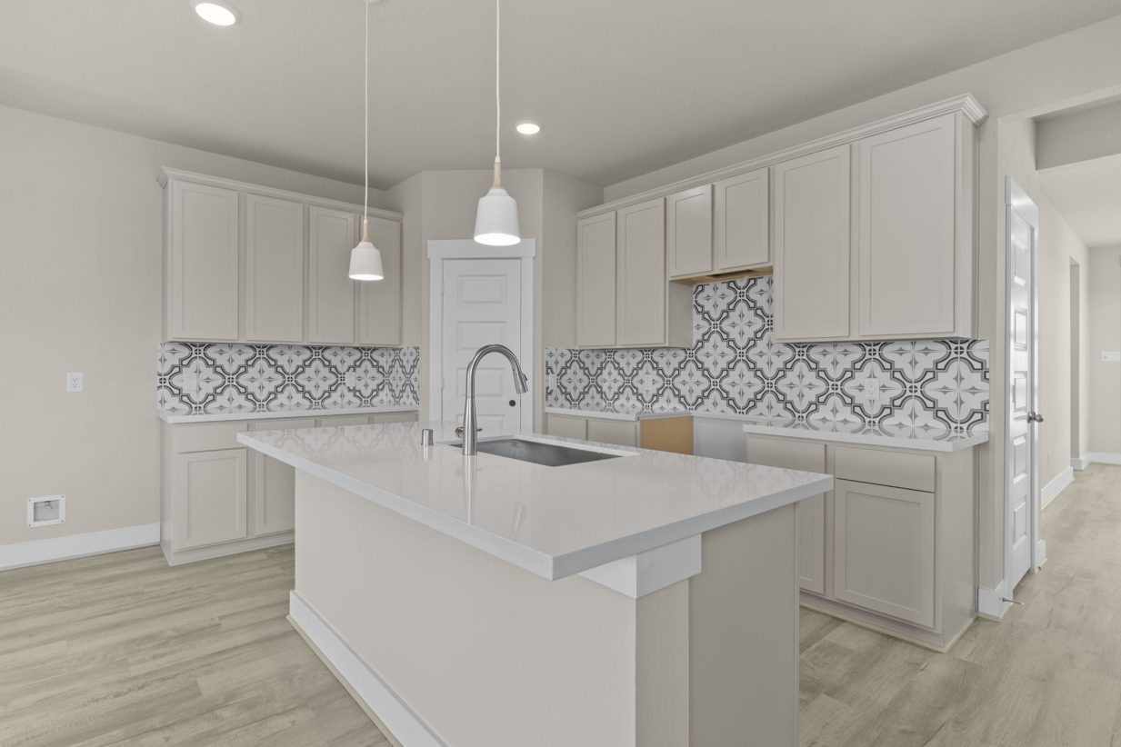 Image of a kitchen with a designed backsplash, beige cabinets, a center island and white countertops