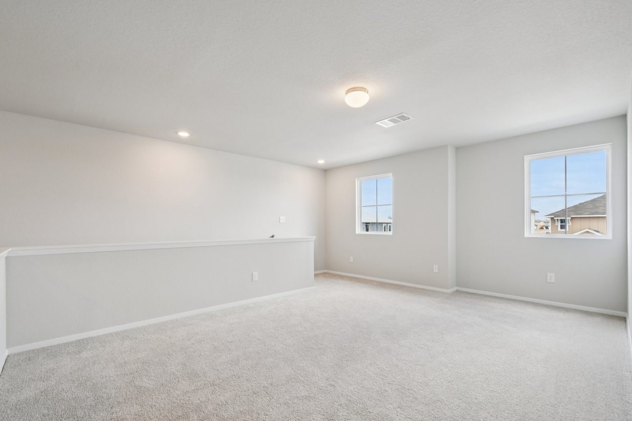 Image of an upstairs recreation area with tan carpeting, light grey walls, and a window