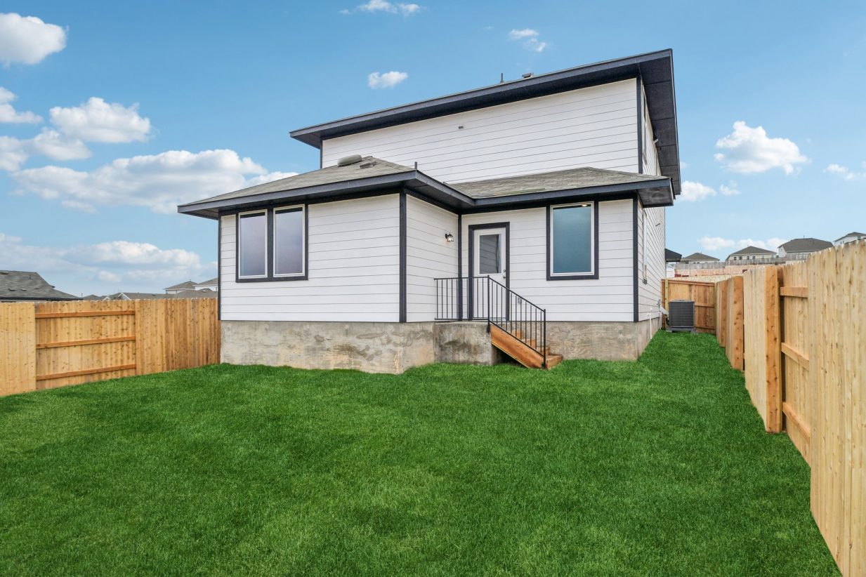 Image of a white two story house backyard with a wooden fence