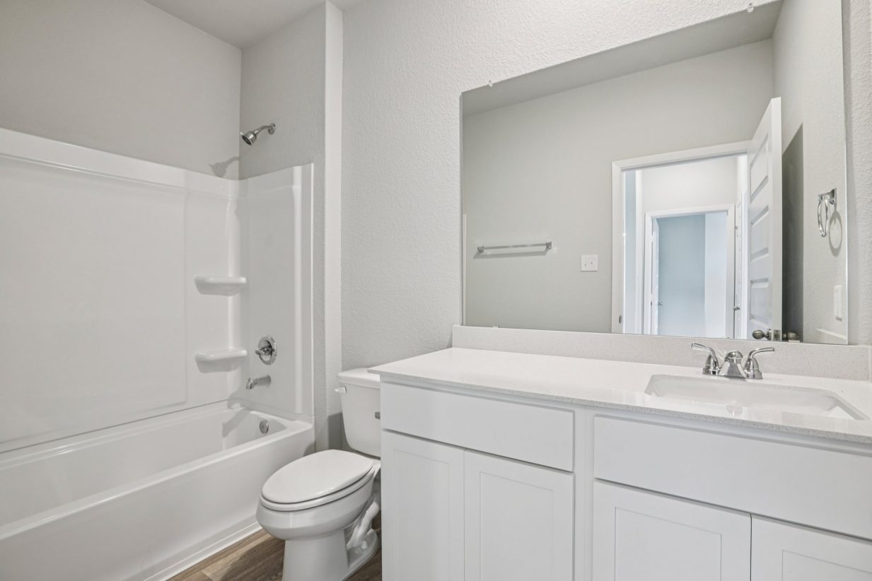 Image of a bathroom with white cabinets, dual vanity, a mirror and a shower with a tub