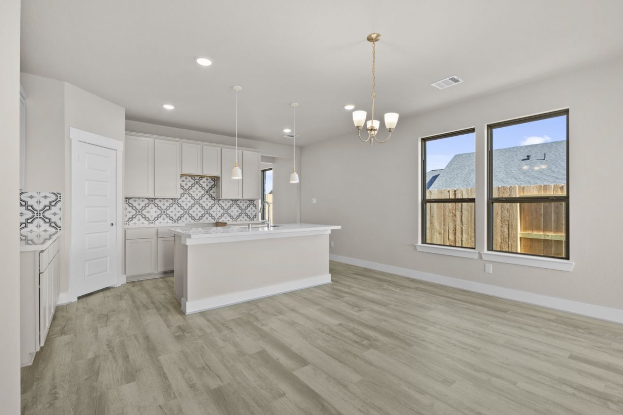 Image of a living room with beige walls, windows with brown trim, and light brown flooring