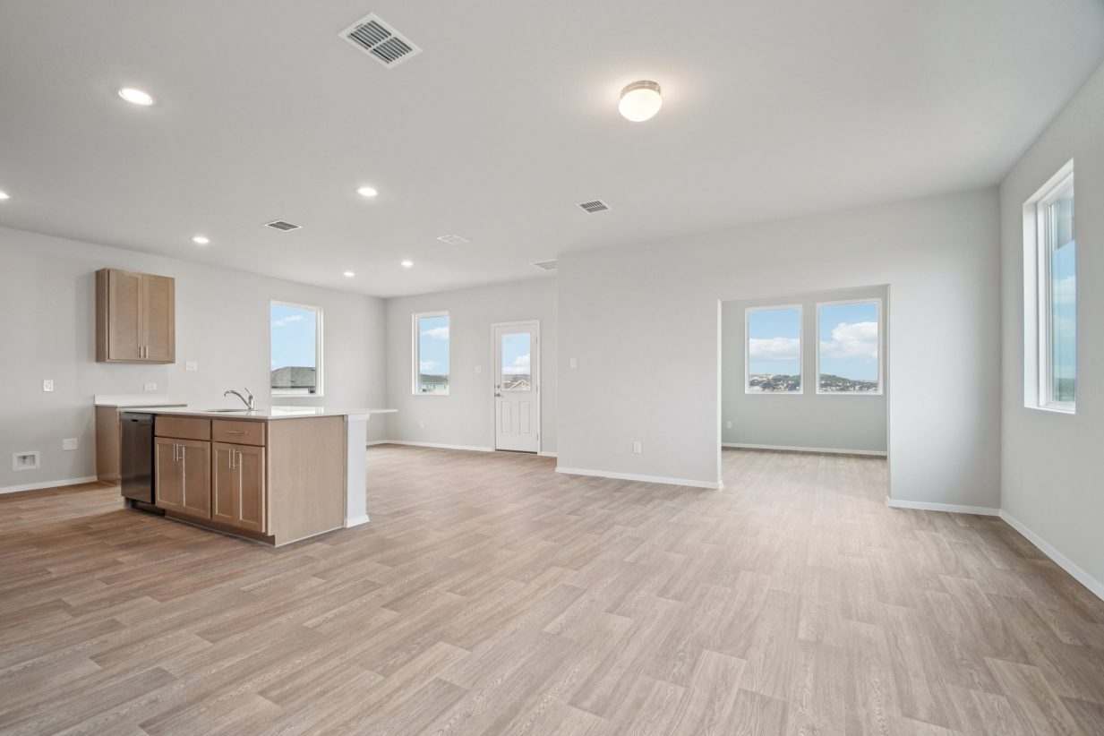 Image of a living room area with light grey walls, vinyl flooring and windows
