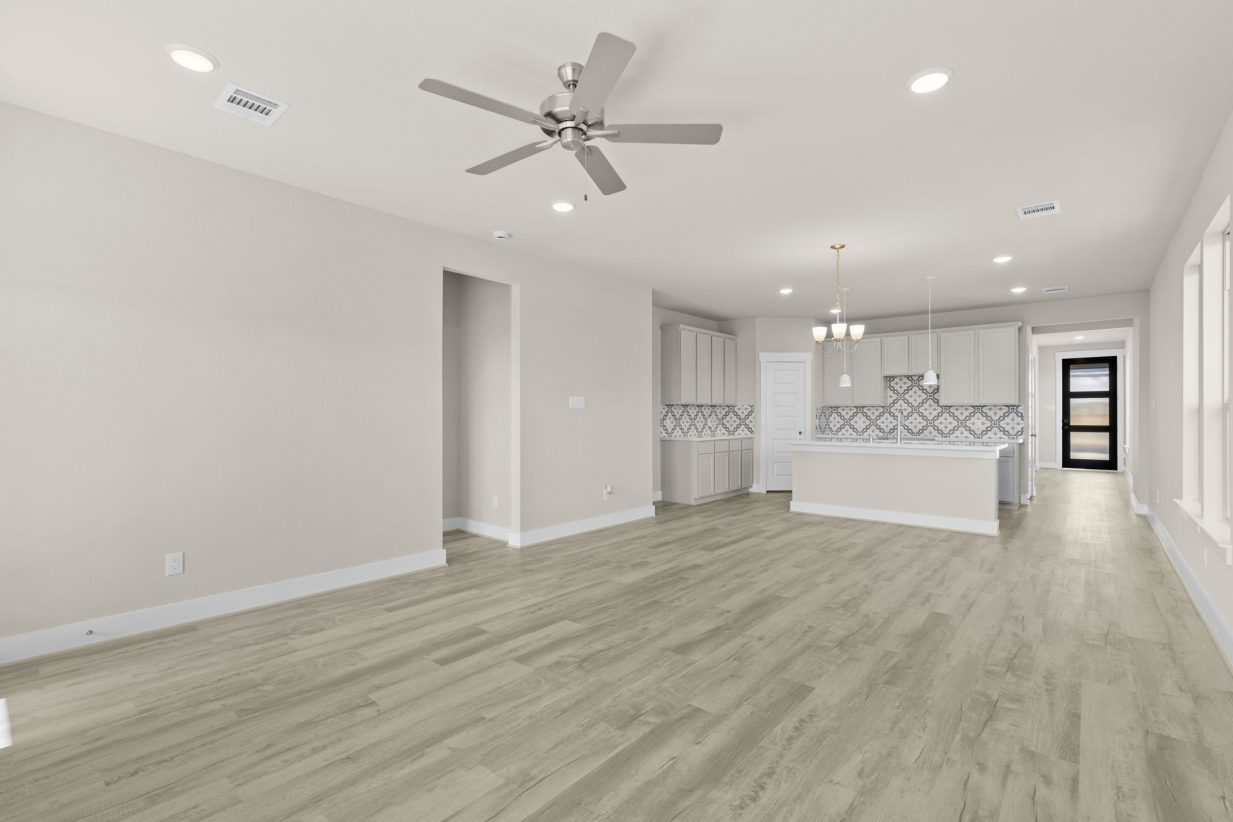 Image of a living room with beige walls, light brown wood-look flooring and an open kitchen in the back left