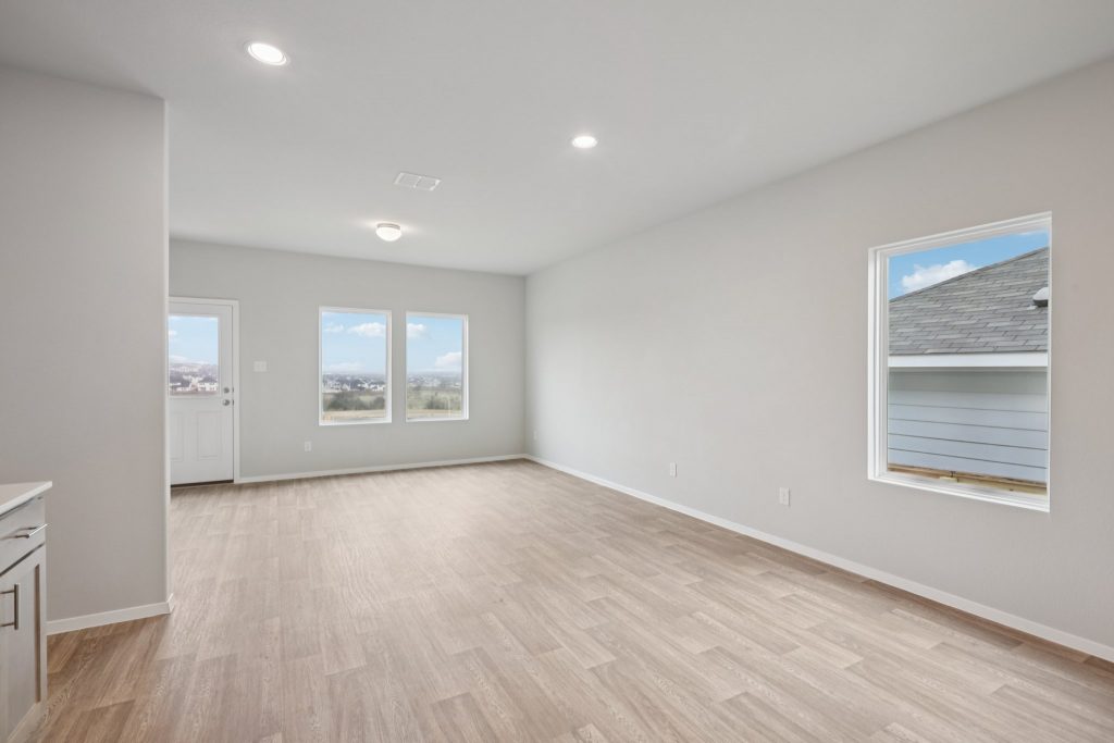 Image of a living room with light grey walls, vinyl flooring and windows