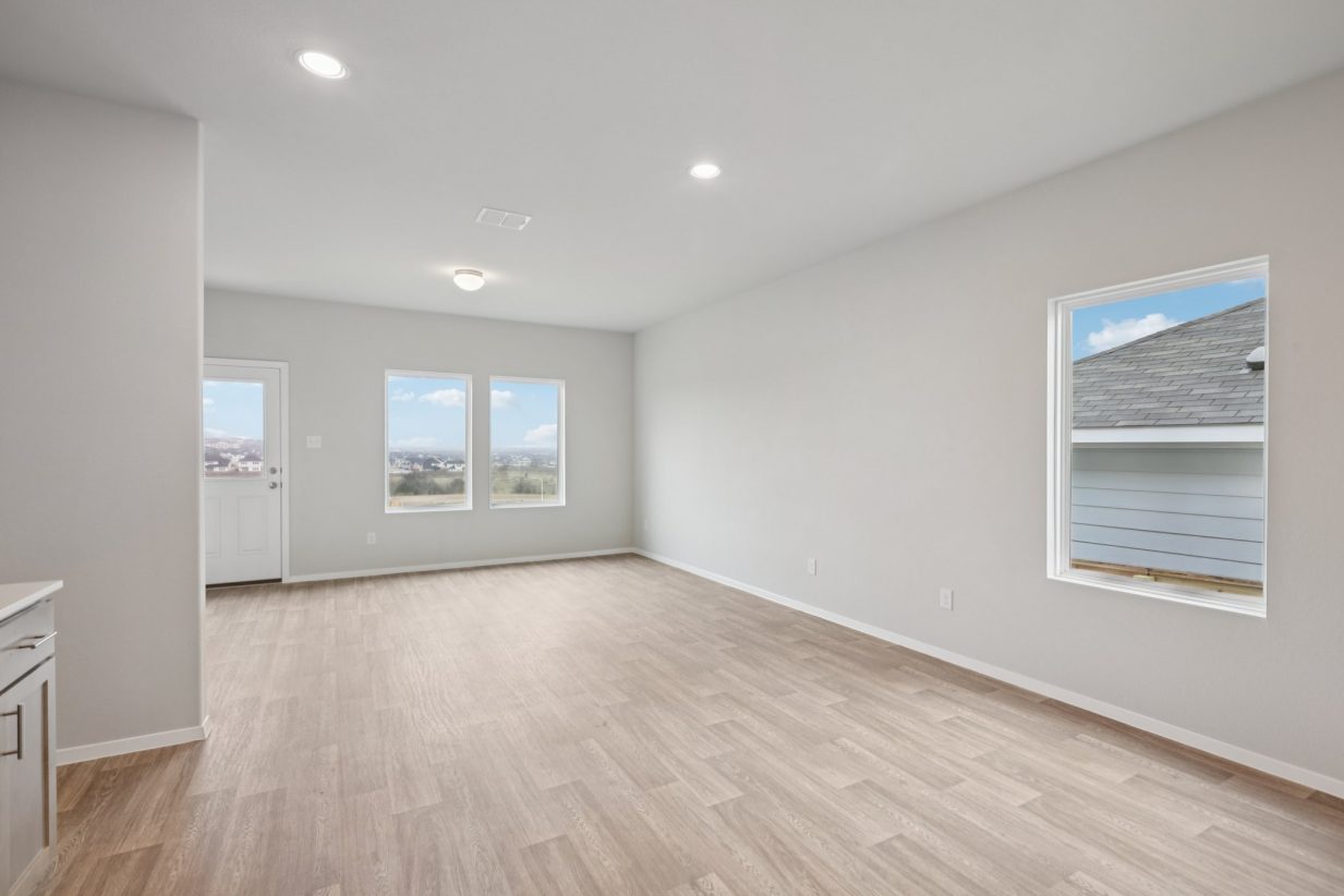 Image of a living room with light grey walls, vinyl flooring and windows