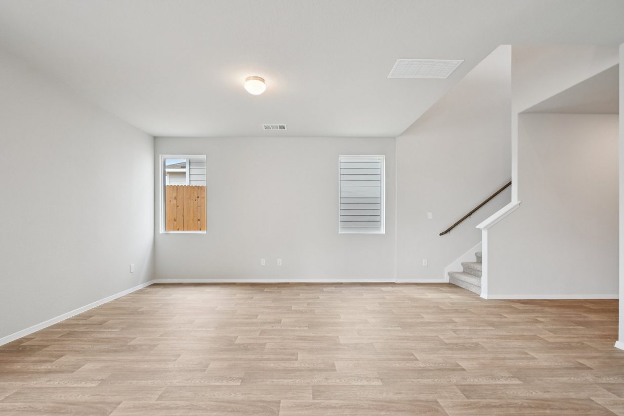Image of a living room with light brown vinyl flooring, grey walls, windows and white trim