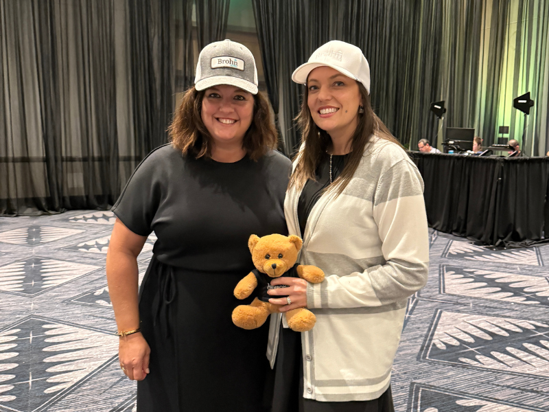 An image of two women wearing hats holding a teddy bear.