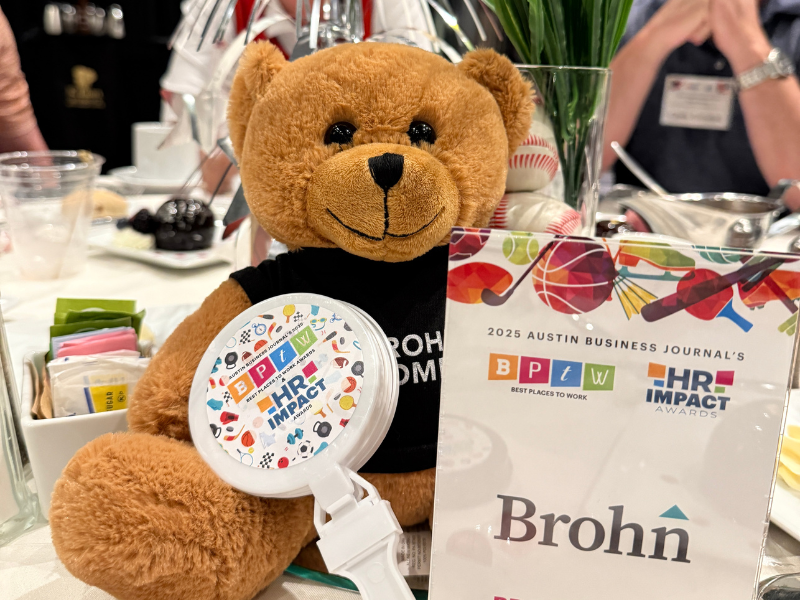 An image of a teddy bear holding a clapper toy and next to sign with the words Brohn on it.