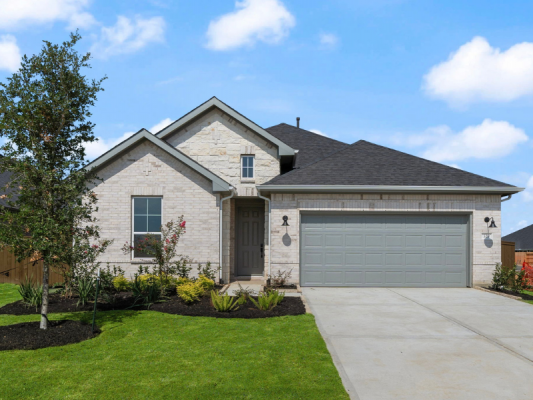An image of a single story brick home with a gray garage door, green grass lawn, concrete driveway, and a blue sky with clouds in the background.