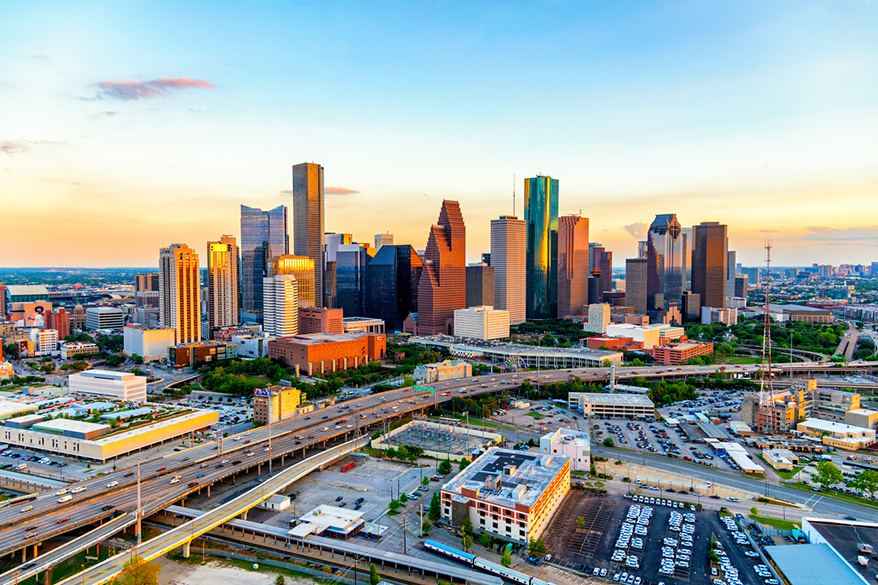 A landscape photo the Houston City Skyline with a sunset in the background.